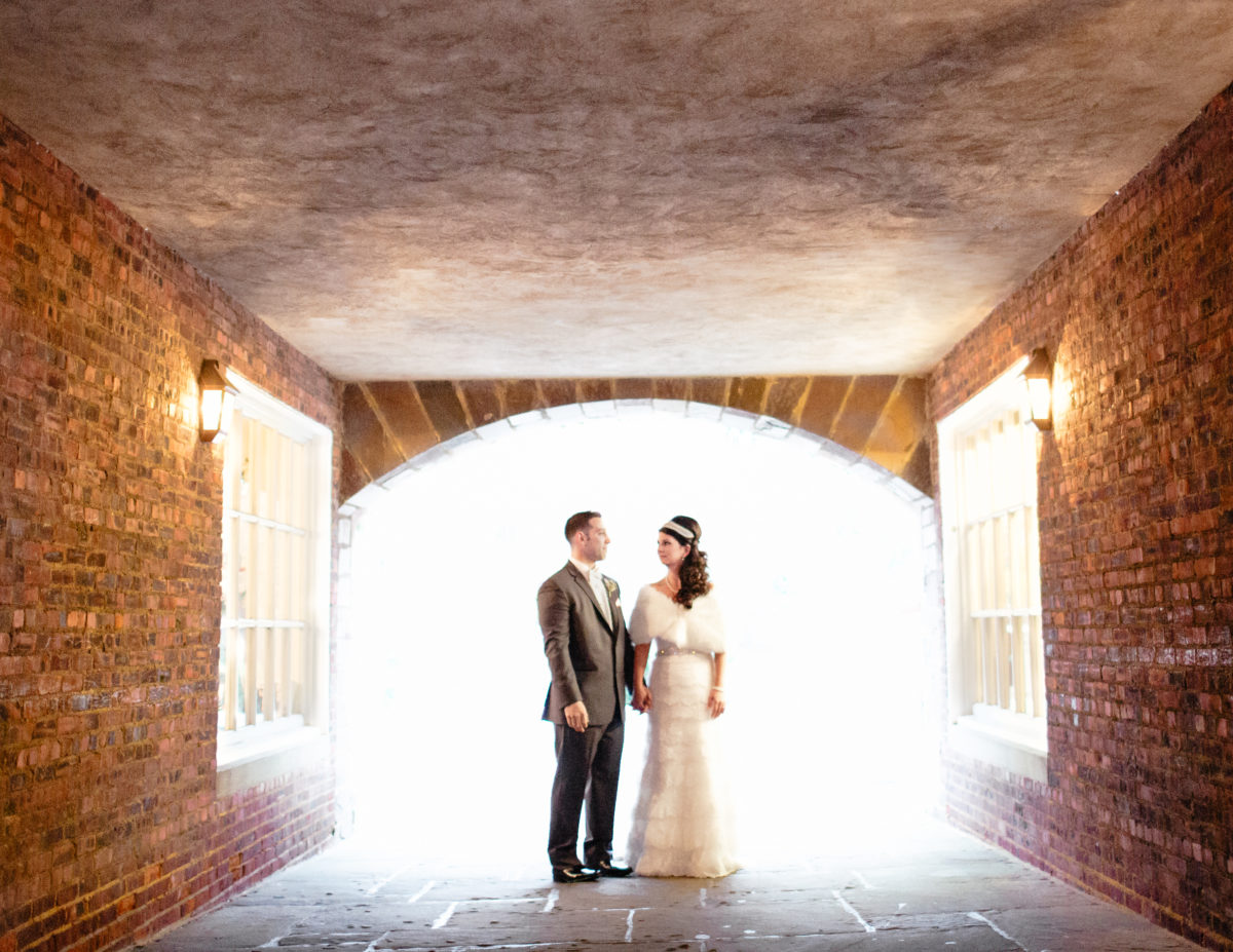 bride and groom looking at one another under archway outside