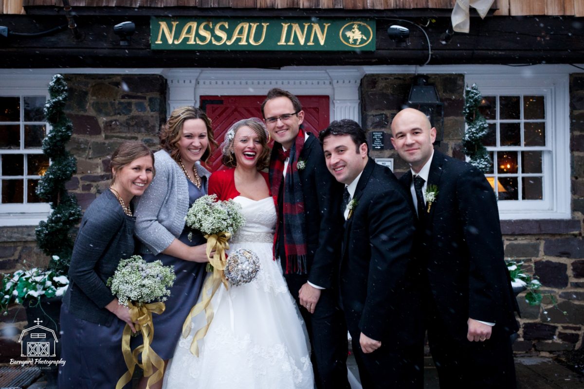 bridal party smiling in front of Nassau Inn red door