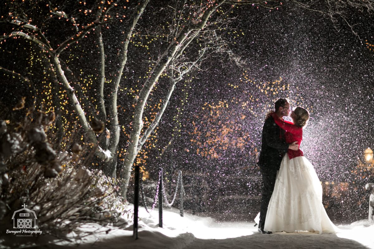 bride and groom kissing outside as snow falls