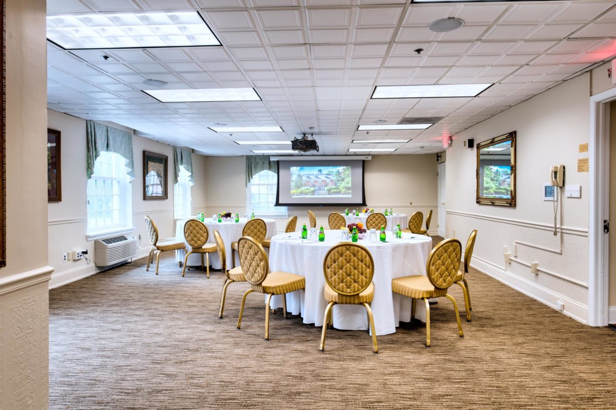 banquet room with three tables set with chairs and projector
