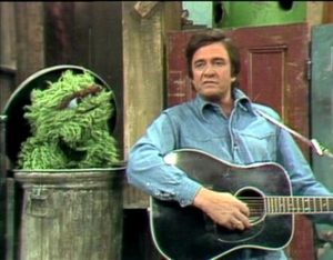 Johnny Cash playing guitar next to Oscar the Grouch