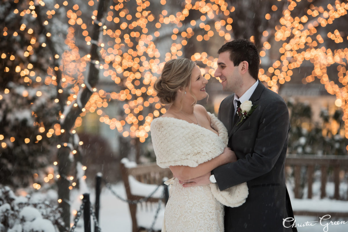 bride and groom gazing at each other as lights twinkle and snow falls