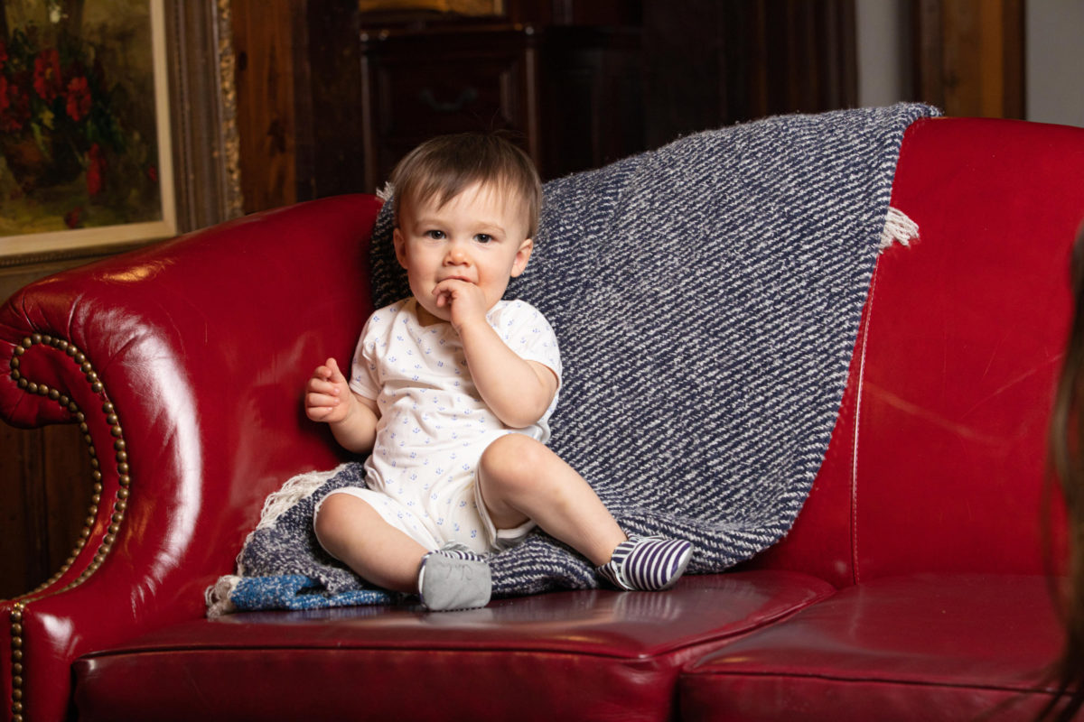 baby boy sitting on red leather couch