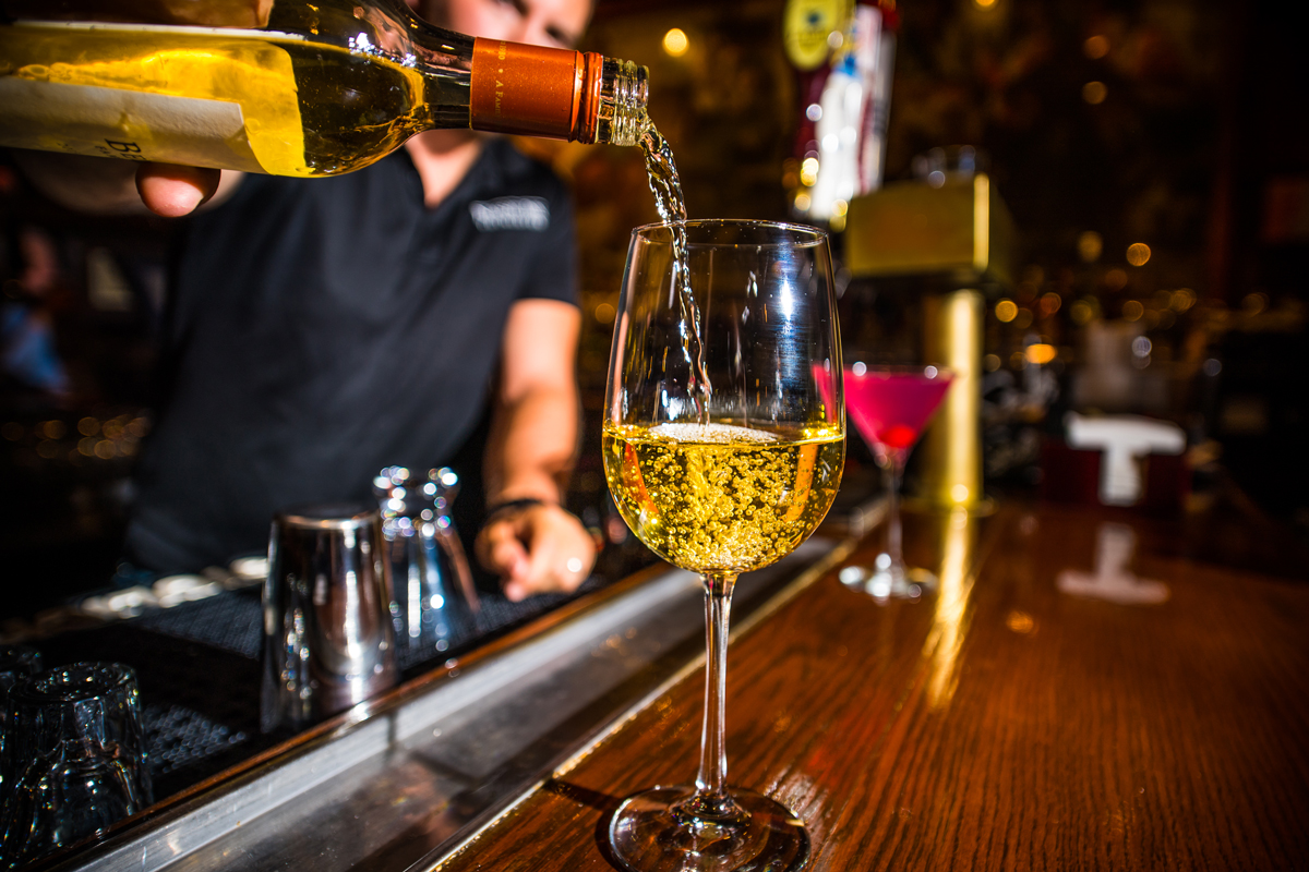 pouring white wine into a glass at the Yankee Doodle Tap Room bar