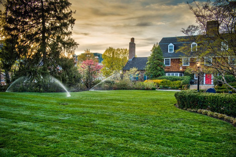 sprinklers spraying lawn with hotel red door in the background