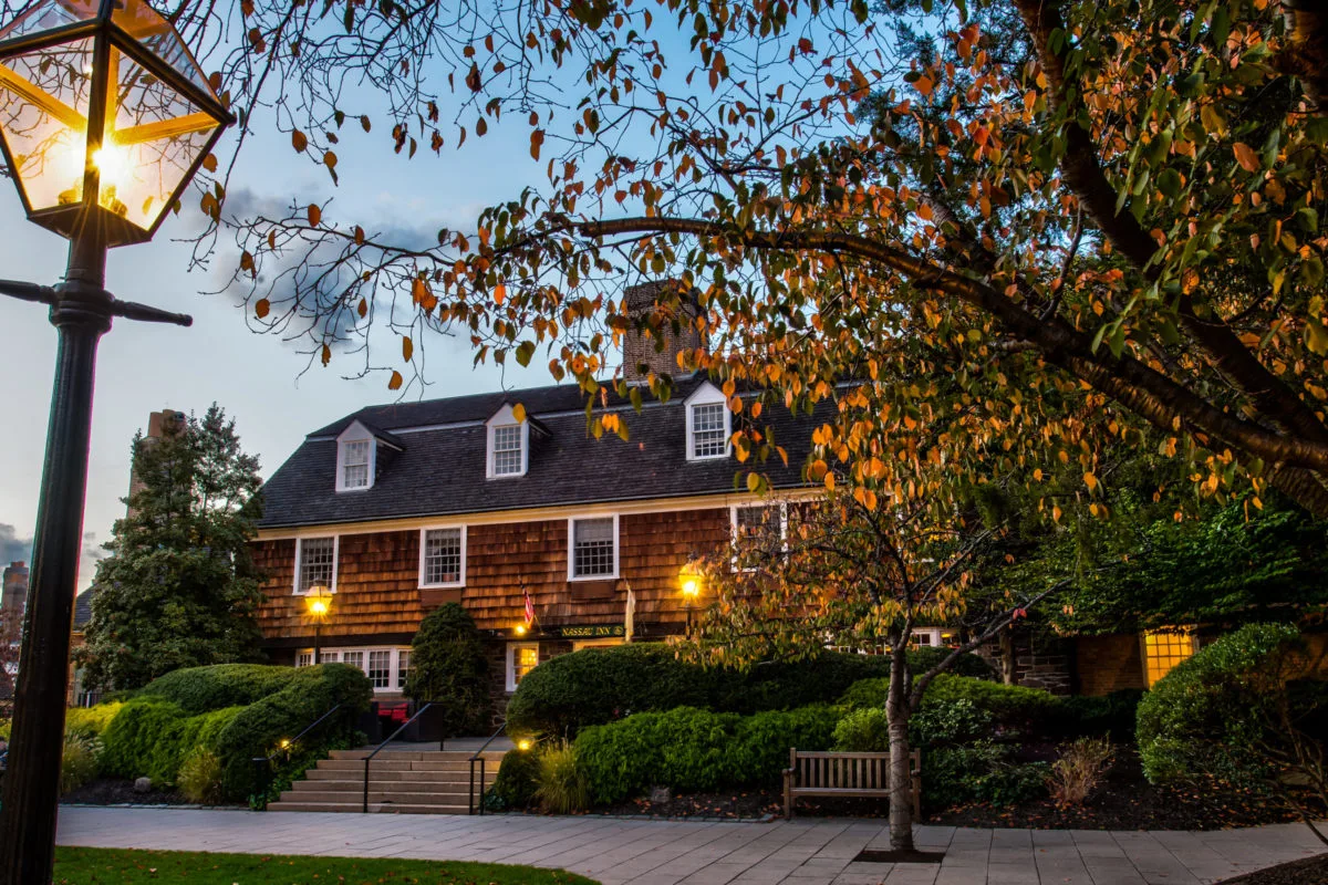 autumn leaves falling from tree at dusk with Nassau Inn hotel in the background