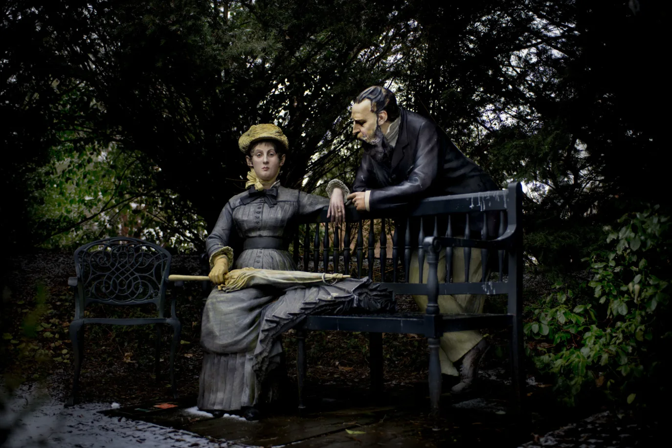 A sculpture of a man and a woman at a park bench.